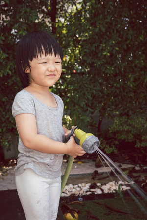 Funny moment of 3 Year old asian kid playing water with garden hose in backyard. Background concept  for play time and summer of children.の写真素材
