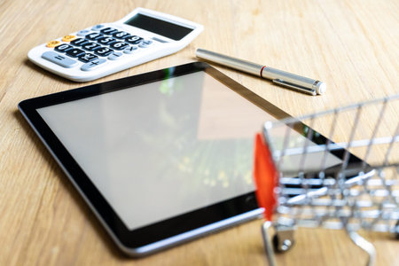 Top table  shopping cart  and calculator on wooden surface. Concept for money calculation for life.