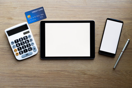 Top view  shopping cart and mobile phone mock up on wooden surface. Concept for money spending and financial backgroundの写真素材