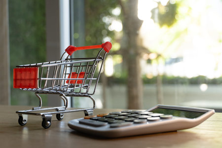Close up shopping cart and calculator on wooden surface. Concept for money spending and financial...