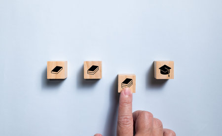 Top view wooden blocks set route from book icon to graduate icon. Concept for learning and education.の写真素材