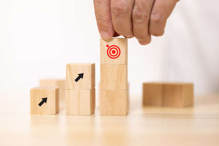 Close up hand stack Wooden block to upside bar graph. Concept for growth graph and route to target.の写真素材