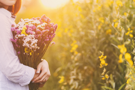 Lady, hands holding a bouquet of statice flowers, soft, spring sunsetの写真素材