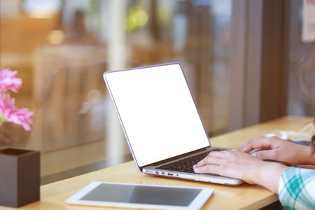 Freelancing woman using laptop computer for distance job while sitting in coffee shop. Business...