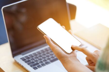 business woman using smart-phone on wooden table with laptopの写真素材