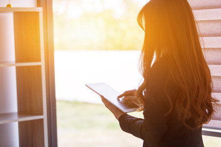 Close-up of female hands typing on touch screen of digital tablet outside, Business woman using a tablet in the office.の写真素材