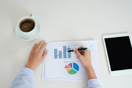 Business women hand with Financial charts and laptop on the table. report papers and Office table,...