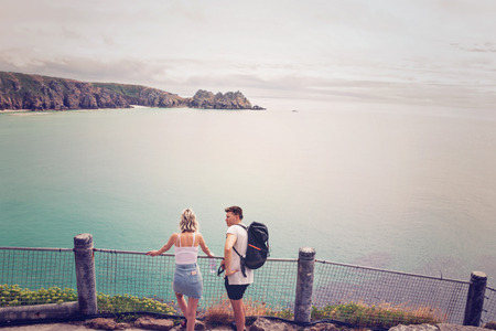 Porthcurno, Cornwall, England - July 24, 2018: Couple looking  over Pedn Vounder beach and Logan Rock seen from Minack Open Air Theatre; Cornwall; England; UKのeditorial素材