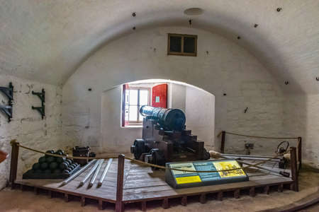 26 July 2018 - Dartmouth, Devon, UK: A black cannon sits peacefully on a wooden gun carriage facing a gun port closed by a window in the tower of Dartmouth Castleのeditorial素材
