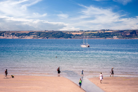 25 July 2018: Marazion, Cornwall, UK-Tourists walk along the beaches of Marazion, an ancient market...