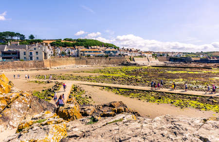 25 July 2018: Marazion, Cornwall, UK-People walking on the causeway coming back from St Michaels Mount  in Cornwall Britain. At low tide, the island can be reach by foot from Marazion town by a man-made causeway.のeditorial素材