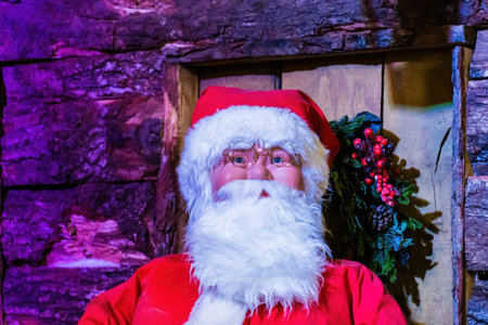Close up face shot of Santa Claus smiling and wearing glasses. Christmas decorations on sale in a...