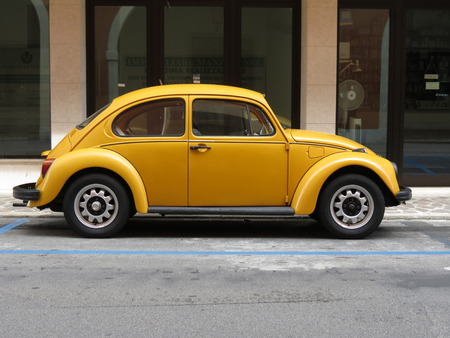 TREVISO, ITALY - CIRCA JULY 2014: Yellow Beetle vintage car parked in a street of the city centre.のeditorial素材