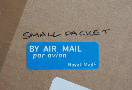 LONDON, UK - CIRCA AUGUST, 2015: Small packet handwritten on a parcel - By air mail label by the Royal Mailのeditorial素材