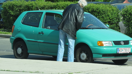 VIENNA, AUSTRIA - CIRCA APRIL 2016: light green Volkswagen Golf parked on the street with owner cleaning itのeditorial素材
