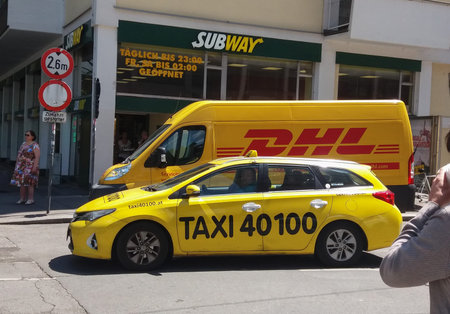 VIENNA, AUSTRIA - CIRCA JUNE 2016: DHL Deutsche post van and yellow taxi car