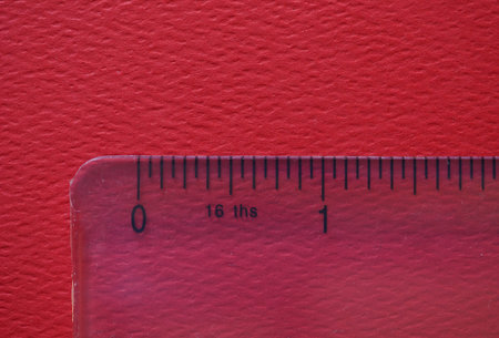 plastic ruler over red paper background showing inchesの写真素材