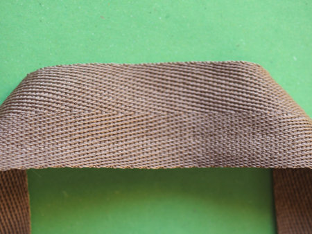 light brown fabric bag handle over green background