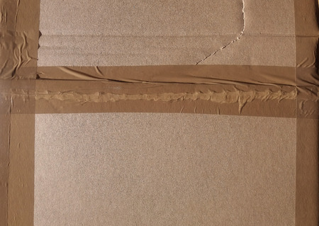 brown corrugated cardboard with adhesive tape band texture useful as a backgroundの写真素材