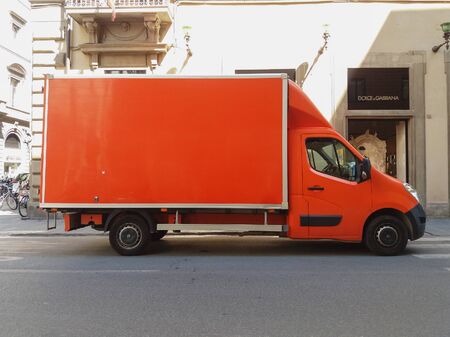 FLORENCE, ITALY - CIRCA APRIL 2019: orange van parked on the street in front of Dolce and Gabbana fashion brand storeのeditorial素材