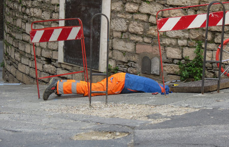 PERUGIA, ITALY - CIRCA APRIL 2019: man working in a manhole with head downのeditorial素材
