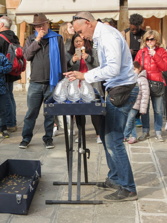 VENICE, ITALY - CIRCA MARCH 2018: unidentified musician playing a glass harp (also called musical...
