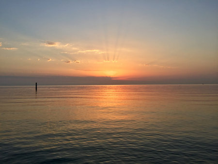 An orange dawn on a motionless sea, almost an iridescent slab of marble.