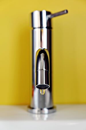 close up of tap leaking on yellow backgroundの写真素材