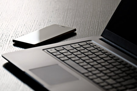 smartphone and laptop on a wooden table