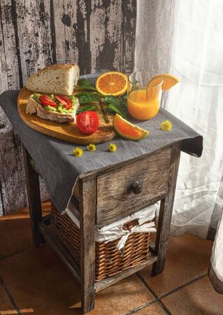 Healthy vegetarian breakfast with bread, avocados, tomatoes and orange juice, prepared at home during the quarantine.の写真素材