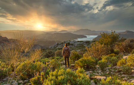 Woman looking at immense lonely and tranquil landscape at sunsetの写真素材