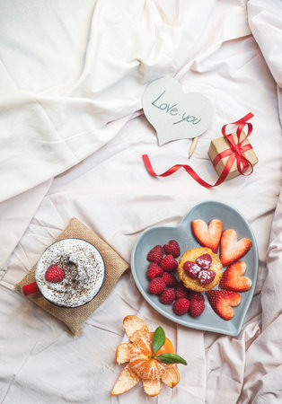 Breakfast in bed. A cup of coffee, cappuccino. Breakfast with berries, heart, strawberries and...