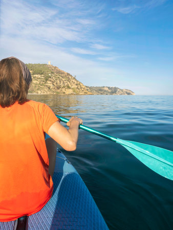 MarÃ³, Spain. Woman paddling on paddle surf board in the Alboran Sea. Woman on vacation on sup board in the calm sea. Maro beach background.の写真素材