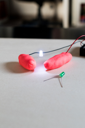 Electronic soft circuits with LEDs, batteries and modeling clay. Set for electronic education for children. Stem activity with green leds lights onの写真素材