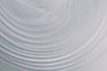 circular wave motion in a fluid system. blue gray background for a liquid pushed into a circular motion. waves and concentric circles with ripples as abstract and generic background. simulation of fluの写真素材