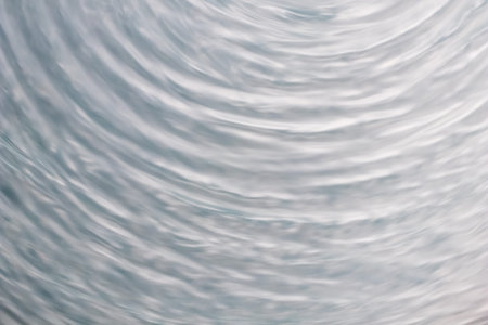 circular wave motion in a fluid system. blue gray background for a liquid pushed into a circular...
