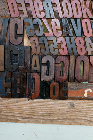 black, red and brown fonts made of wood and embossed in a wooden wall. stamps placed on a wooden wall. Different typed letter letters with different styles, bold, plain and italicの写真素材