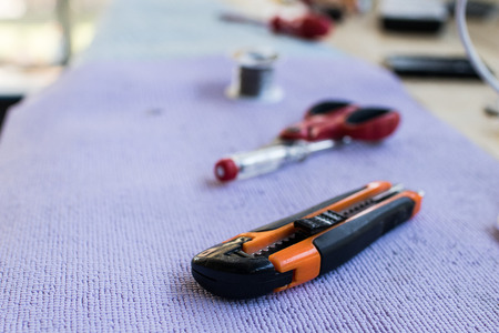 scissors, cutter and screwdriver on a table. Tools of an electrician worker placed in a row on a violet carpetの写真素材