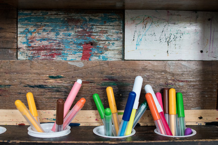 three marker pens with different colors on a wooden shelf with rustic and colorful backdrop. tools for childrenの写真素材