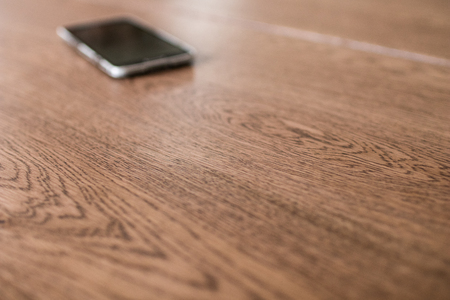 wooden meeting table with blurred smartphone in the background. Business activity in the morningの写真素材