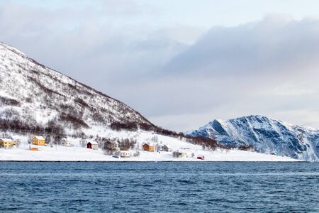 Arctic landscape in winter with snowy mountains and sea. Norwegian coasts and fjords seen from the boat in the open sea. Arctic polar north europe landscape with white snow and iceの写真素材