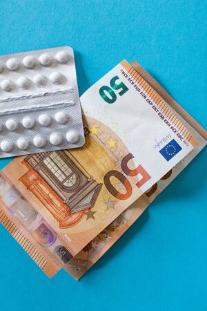 Pills blister on money euro banknotes for pharmaceutical cost. Rising prices of healthcare system. Medical on blue background. Increased costs for coronavirus pandemic. Vaccine and antibioticの写真素材
