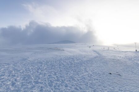 Polar landscape with snow and wind in the mountains. Hiking and snow hiking in the mountains with footprints on the ice and snow. Adventure and excursions in the cold in winterの写真素材
