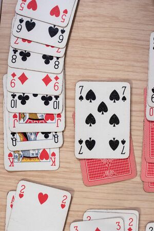French playing cards stacked together in a solitaire. Solitaire game with cards, pastime with signs and cards with red backs and signs of spades and heartsの写真素材