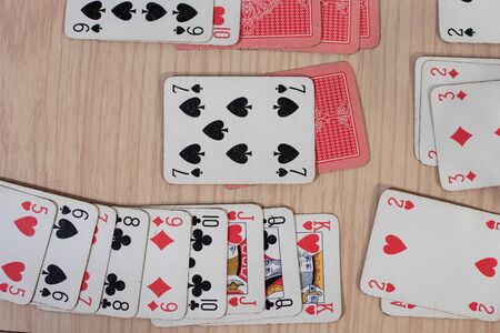 French playing cards stacked together in a solitaire. Solitaire game with cards, pastime with signs and cards with red backs and signs of spades and heartsの写真素材