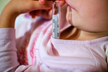 Measure Fever temperature with thermometer to a little child girl, health careの写真素材