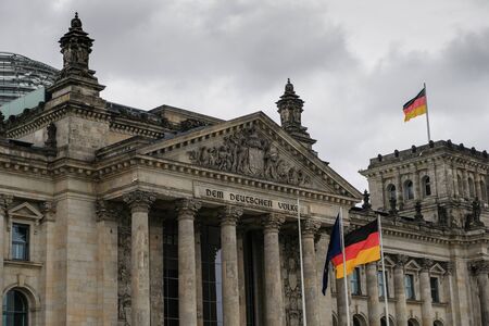 Berlin famous historic reichstag facade with german flags over cloudy sky,symbolの写真素材