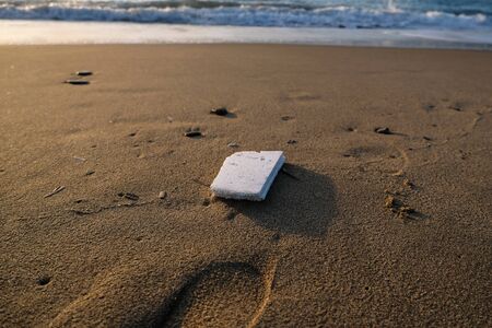 Polystyrene garbage on sandy sea shore on sunset golden light,pollution conceptの写真素材
