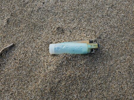 Plastic lighter trash on sandy sea ecosystem,microplastics sea coast pollutionの写真素材