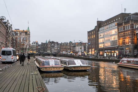 Illuminated moody Amsterdam canals view,touristic boats,traditional architectureのeditorial素材